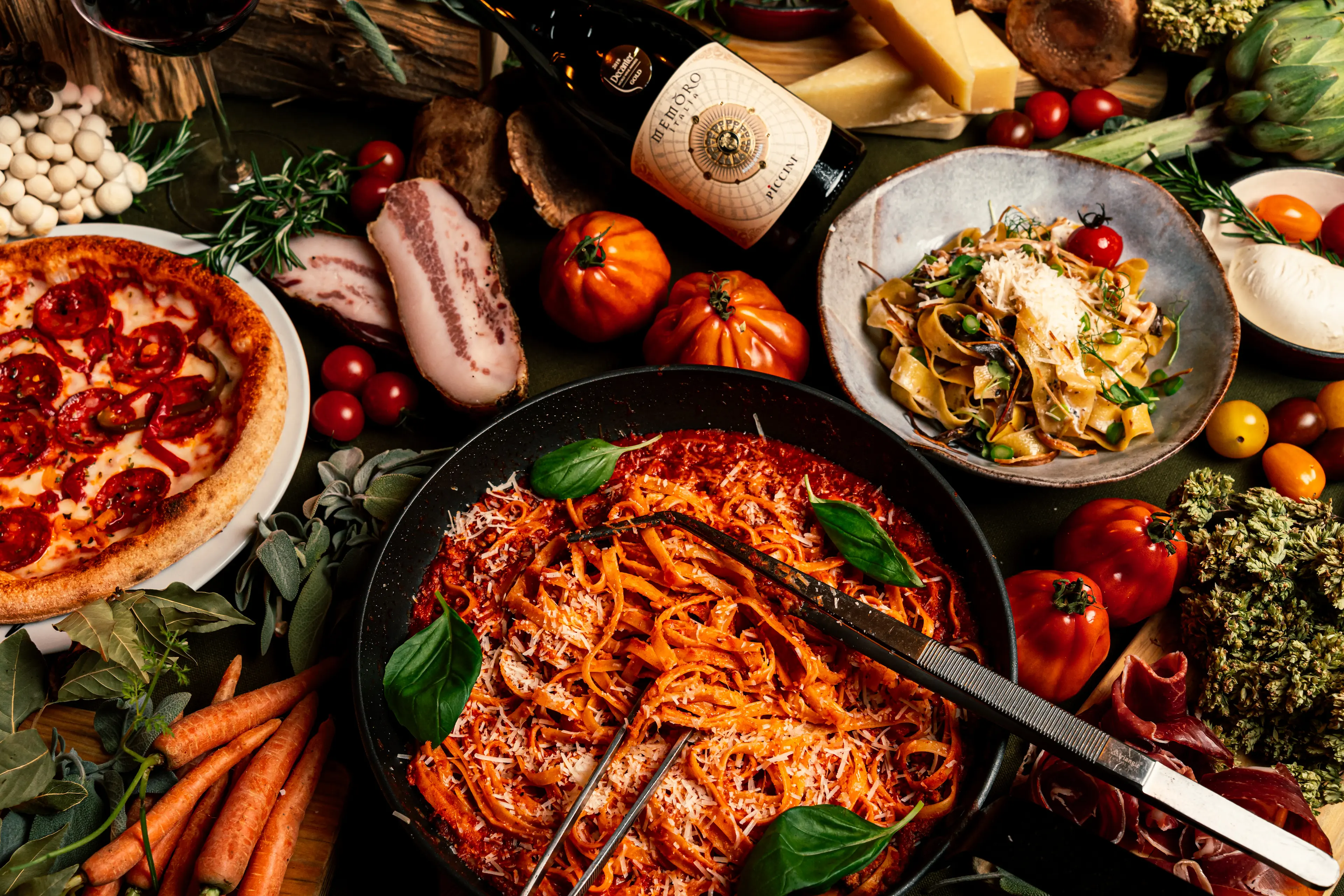 Mesa com vários ingredientes frescos e pratos italianos.